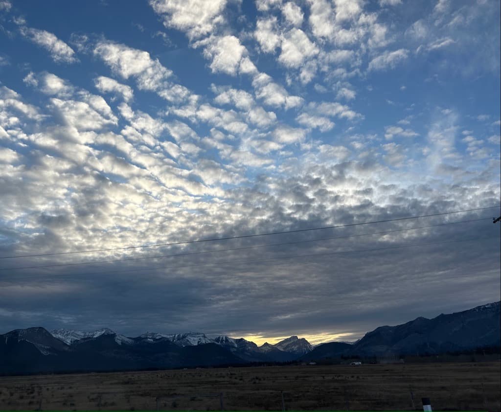 Expansive Alberta sky with mountains on the horizon at sunset